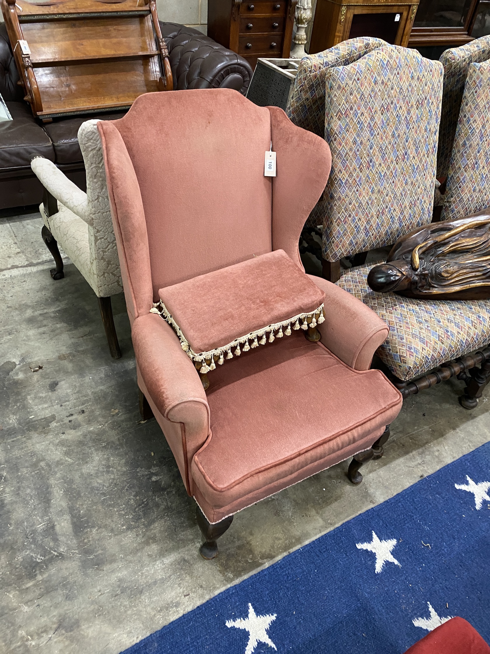 An upholstered wing armchair and footstool